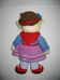 Rövid szőke hajú horgolt kalapos lány piros-kék-lila ruhában